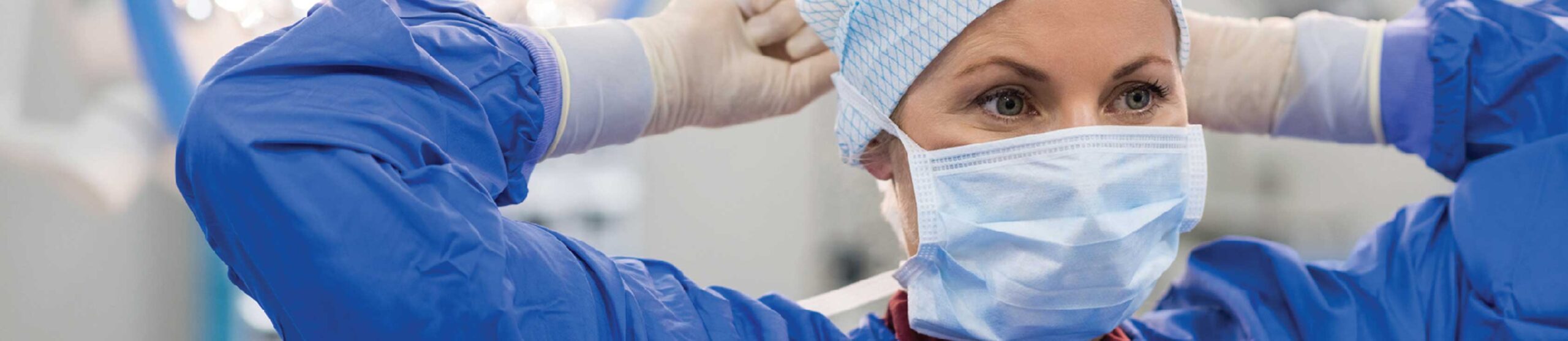 Dr putting on face mask in blue scrubs - Work for us