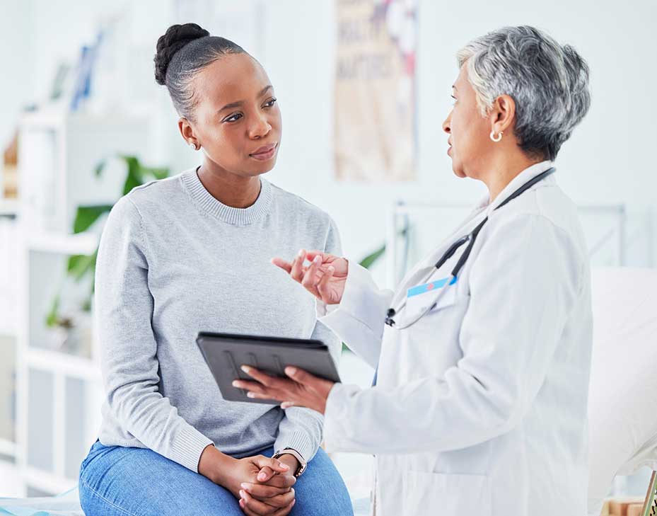 Female Dr talking to a female patient in a bright clean Dr s office
